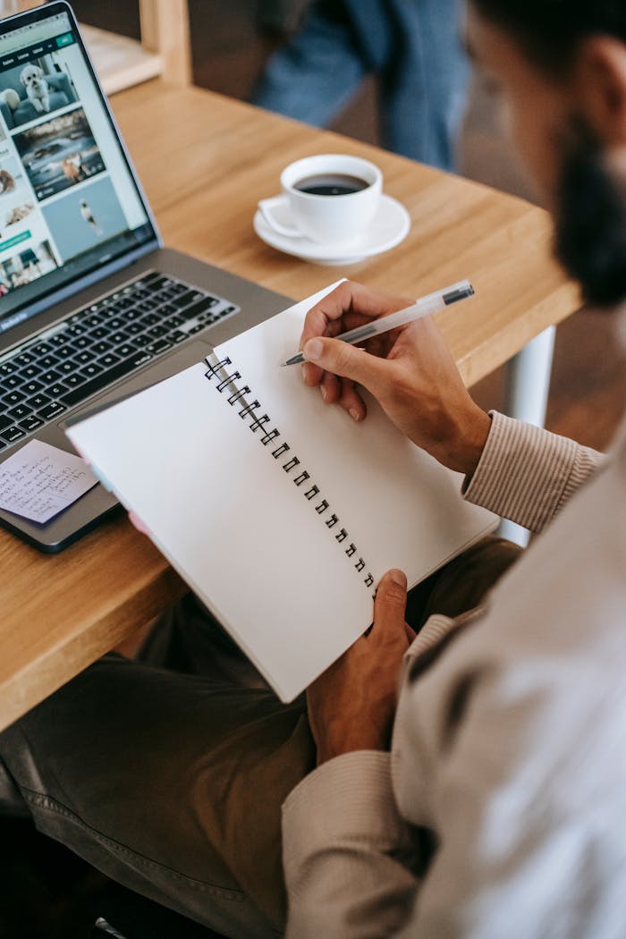 Person Holding Pen Writing On A Notebook